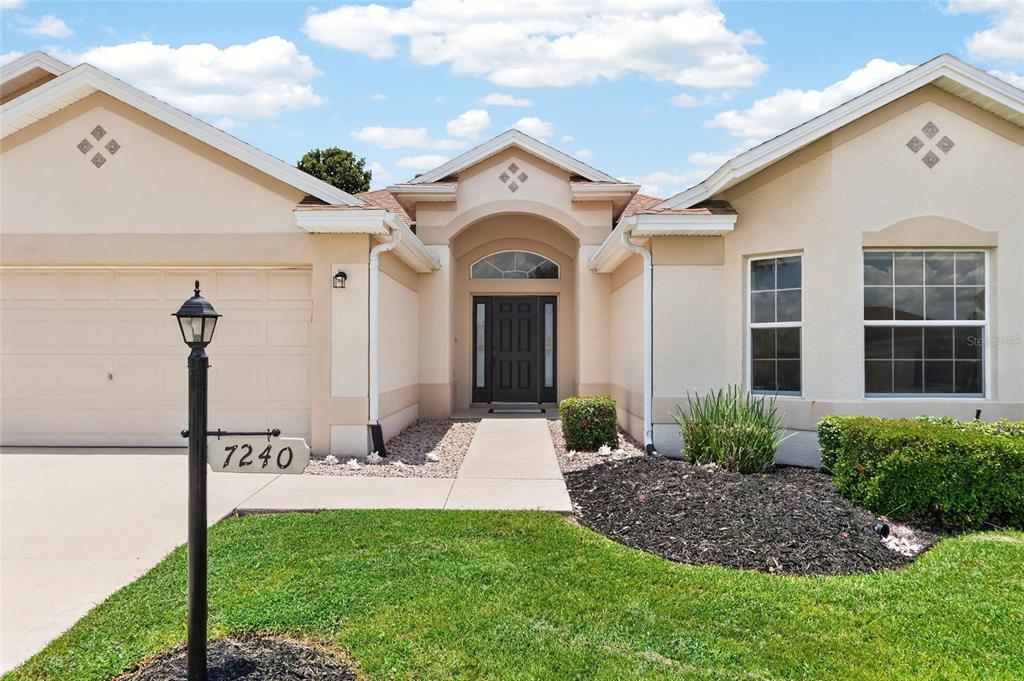 A single-story house with a beige stucco exterior, a two-car garage, and a front walkway — 7240 SE 172ND LEGACY LANE, THE VILLAGES, FL