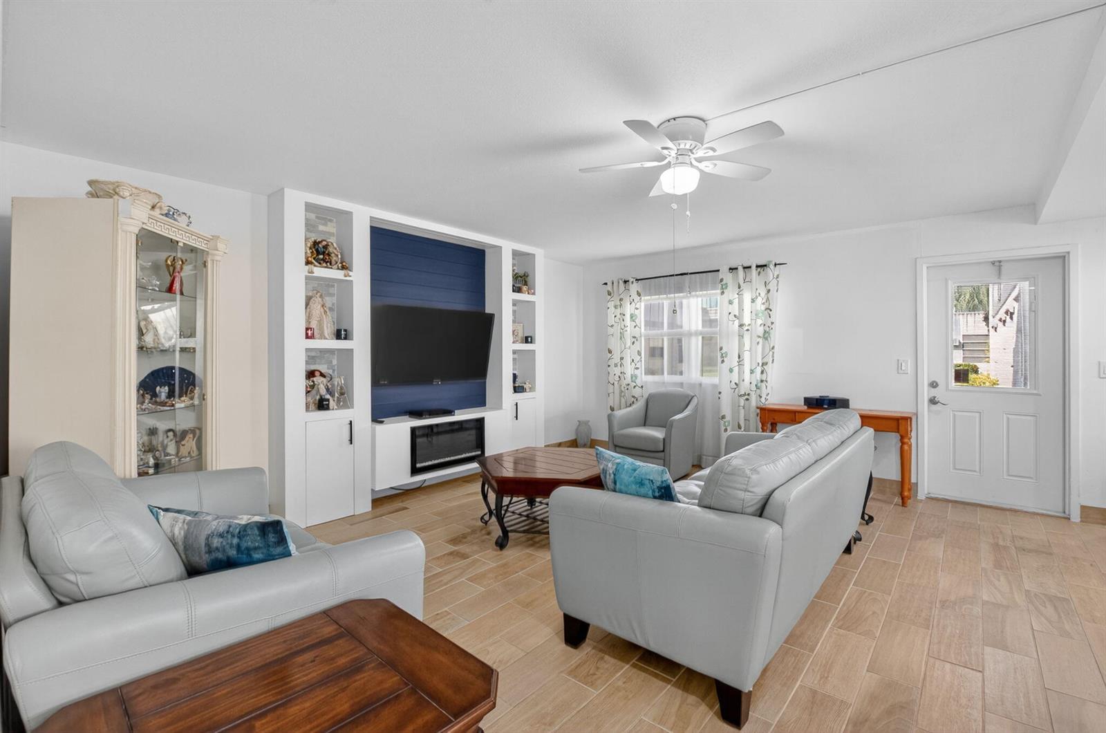 A living room features light tile flooring, a blue accent wall, and gray leather furniture — 60 Brittany # B, Delray Beach FL 33446, DELRAY BEACH, FL