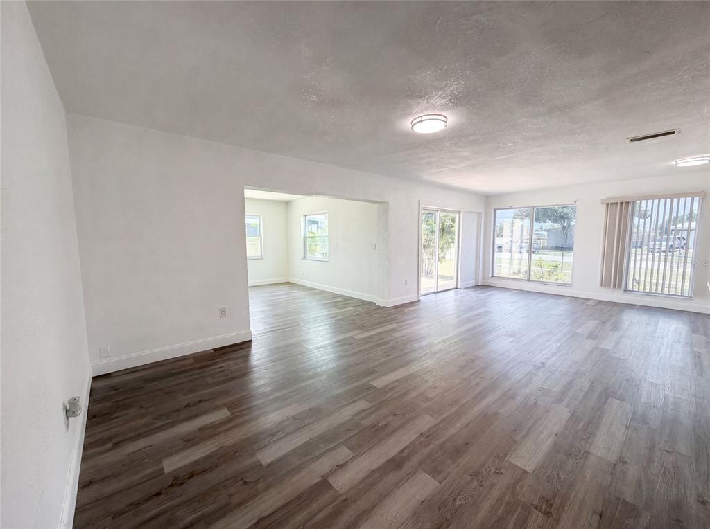 An open-concept living area features light-colored walls, wood-look flooring, and large windows — 21530 GLENDALE AVENUE, PORT CHARLOTTE, FL