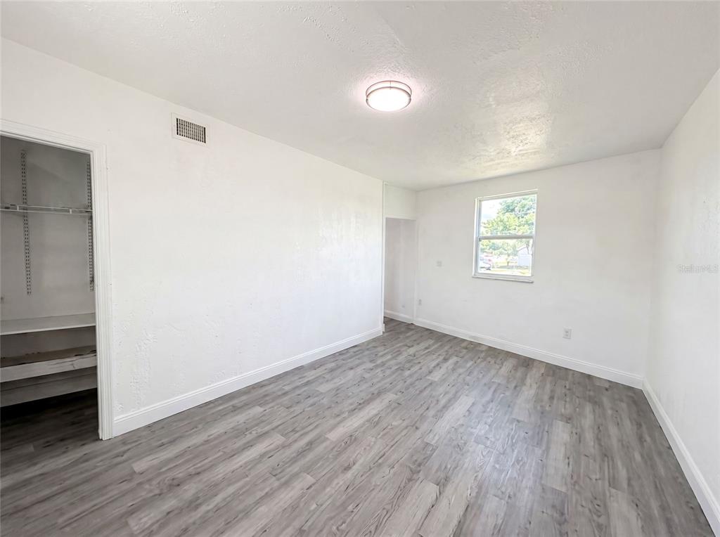 An empty bedroom features white walls, a closet, a window, and gray wood-look flooring — 21530 GLENDALE AVENUE, PORT CHARLOTTE, FL