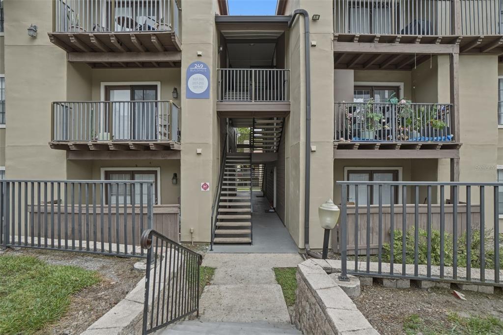 Exterior view of a three-story apartment building with balconies and an open central staircase — 249 AFTON SQUARE UNIT 208, ALTAMONTE SPRINGS, FL