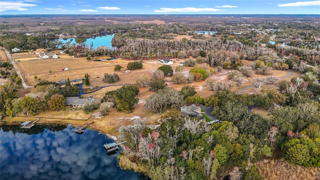 An aerial view shows a large waterfront property with multiple houses, trees, and docks — 8804 MISTY MORNING TRAIL, ODESSA, FL