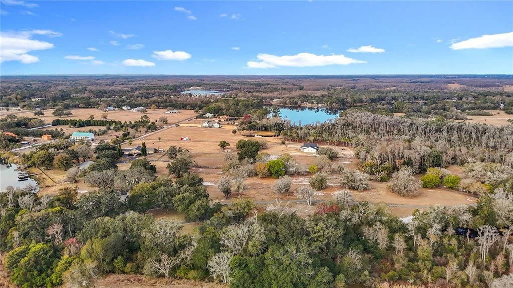 An aerial view shows a rural landscape with scattered houses, trees, and a small lake — 8804 MISTY MORNING TRAIL, ODESSA, FL
