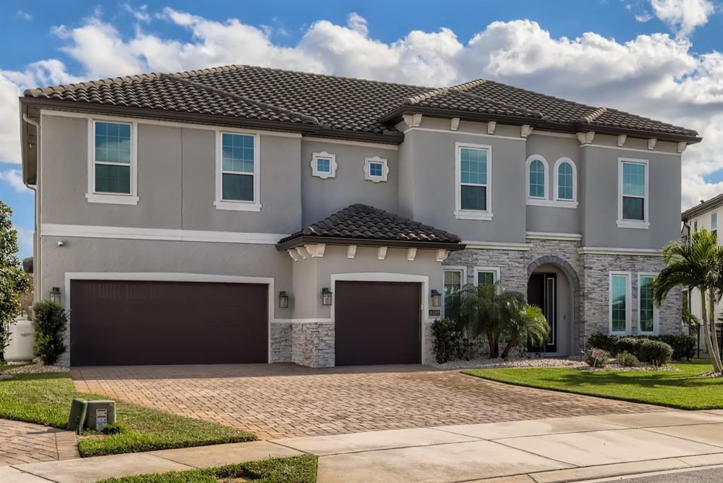 A two-story house with a gray stucco exterior, stone accents, and a three-car garage — 8192 LUDINGTON CIRCLE, ORLANDO, FL