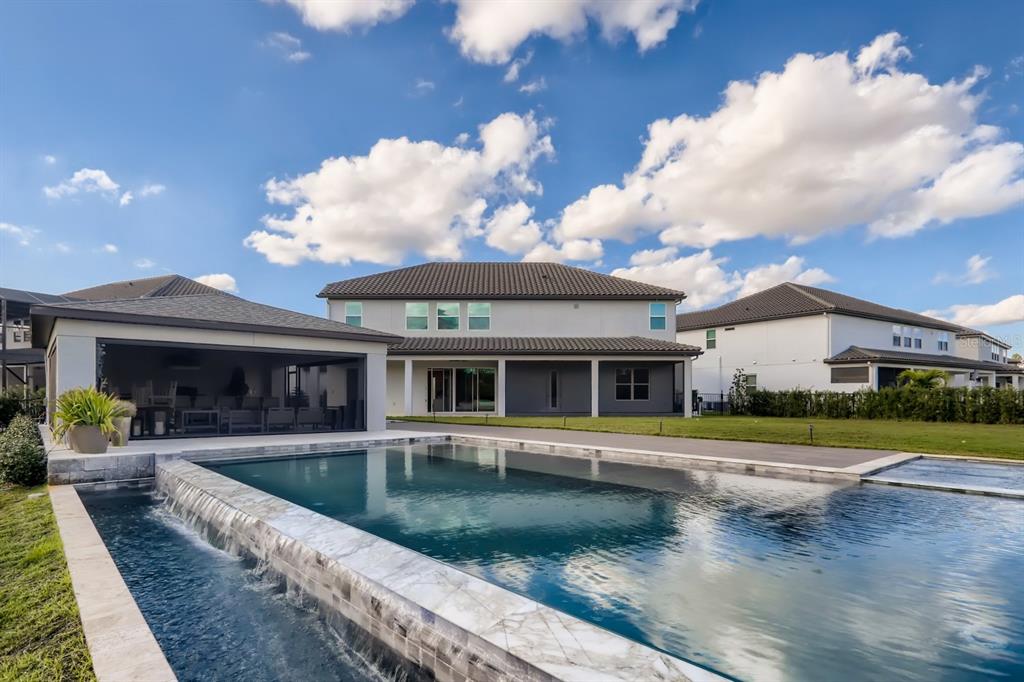 A backyard features a swimming pool with a waterfall edge and a covered patio area — 8192 LUDINGTON CIRCLE, ORLANDO, FL