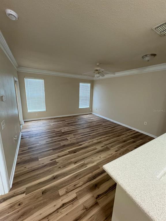 An empty room features wood-look flooring, beige walls, two windows with blinds, and a ceiling fan — 8801 VILLA VIEW CIRCLE UNIT 206, ORLANDO, FL