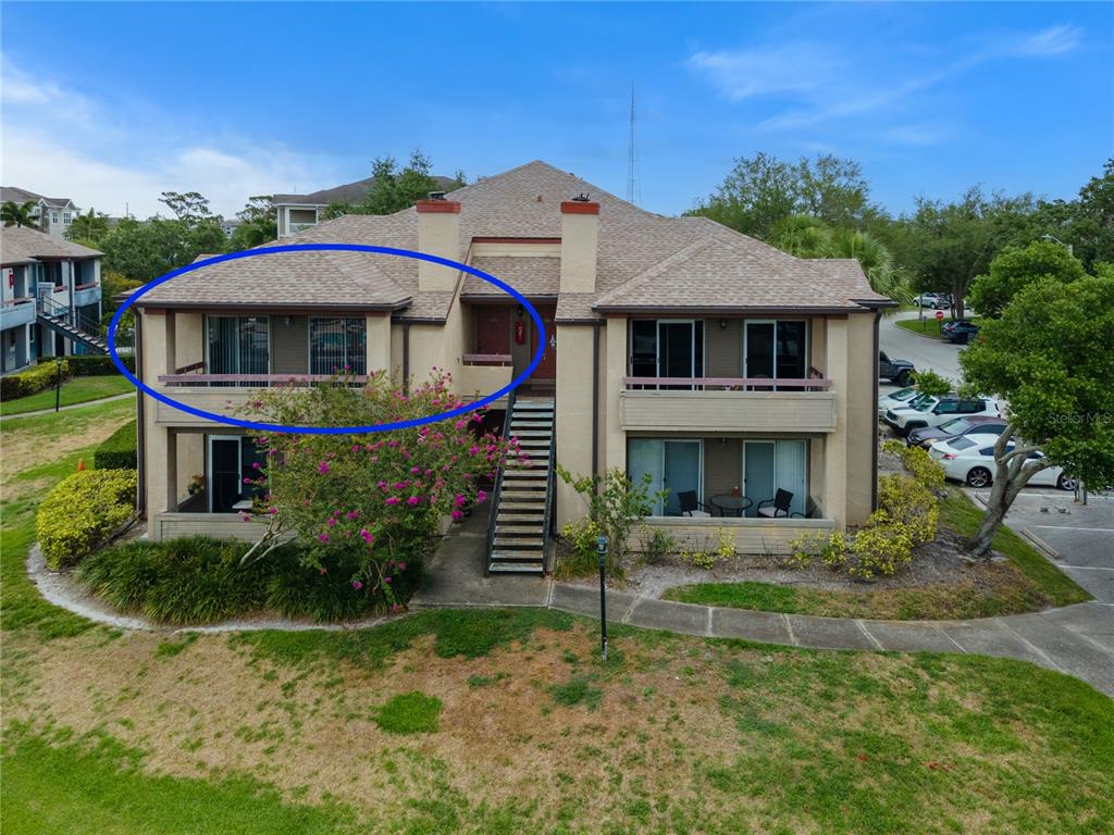 An exterior view of a two-story apartment building with a circled upper-level balcony — 10265 GANDY BOULEVARD N UNIT 914, ST PETERSBURG, FL