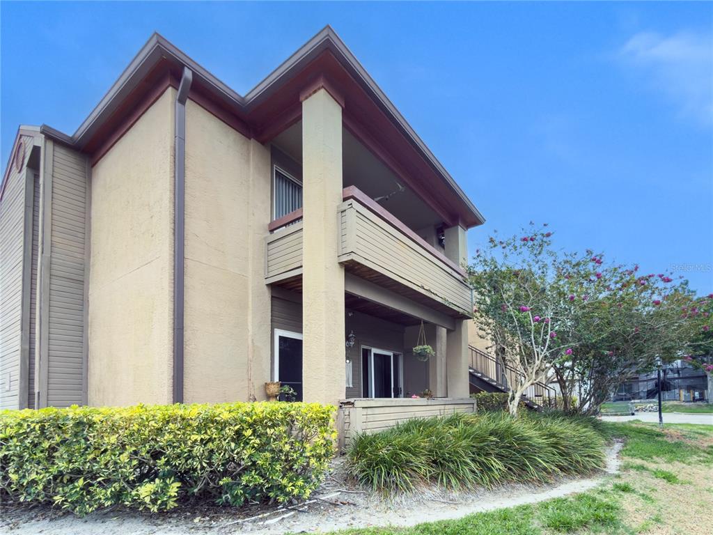 A two-story apartment building exterior features tan stucco walls, brown trim, and private balconies — 10265 GANDY BOULEVARD N UNIT 914, ST PETERSBURG, FL