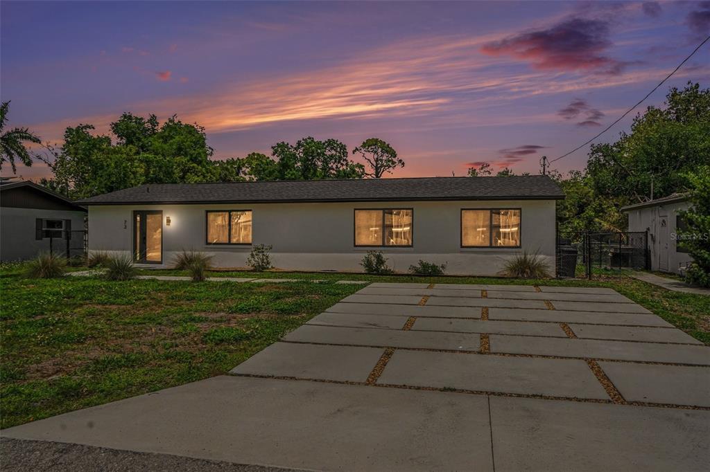 A single-story house with a concrete driveway and a sunset sky in the background — 73 CARDINAL DRIVE, NORTH FORT MYERS, FL