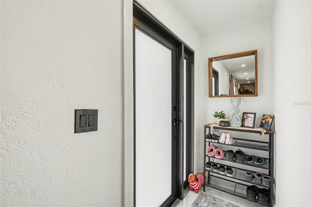 An entryway features a black-framed glass door, a shoe rack, and a wall-mounted mirror — 73 CARDINAL DRIVE, NORTH FORT MYERS, FL