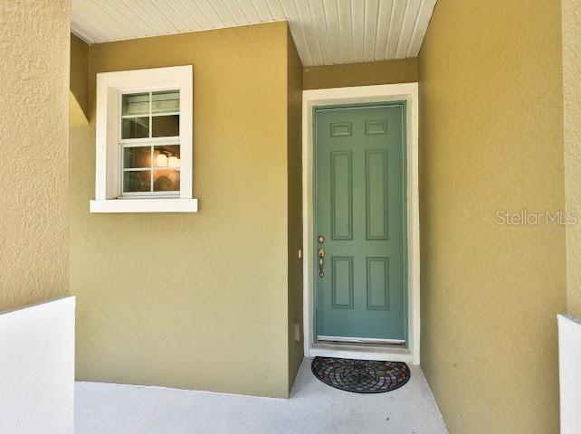 A teal front door and a single window are set into a tan exterior wall — 3893 GLIDING PLACE, SANFORD, FL