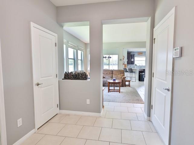 A tiled entryway leads through an opening into a living room with beige furniture — 3893 GLIDING PLACE, SANFORD, FL