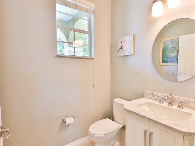 A bathroom features a white vanity with a marble countertop, a round mirror, and a window — 3893 GLIDING PLACE, SANFORD, FL