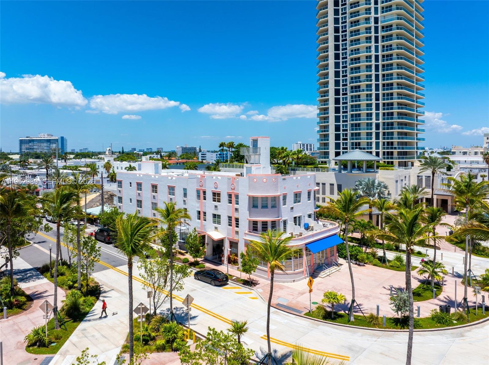 An aerial view shows a white Art Deco building with pink accents near a skyscraper — 7300 Ocean Ter, Miami Beach FL 33141, MIAMI BEACH, FL