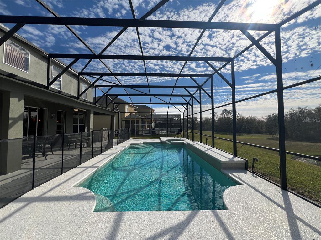A rectangular swimming pool with a spa is enclosed by a screened lanai — 8557 LA ISLA DRIVE, KISSIMMEE, FL
