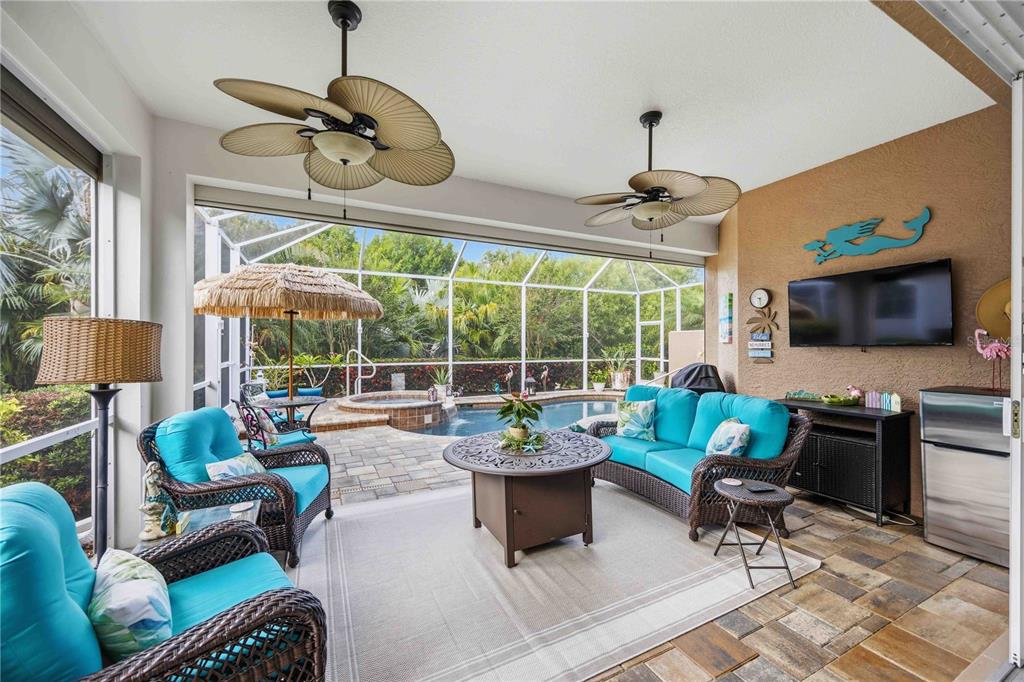 A covered patio features wicker furniture, a fire pit, ceiling fans, and a pool view — 11045 BARNSLEY DRIVE, VENICE, FL