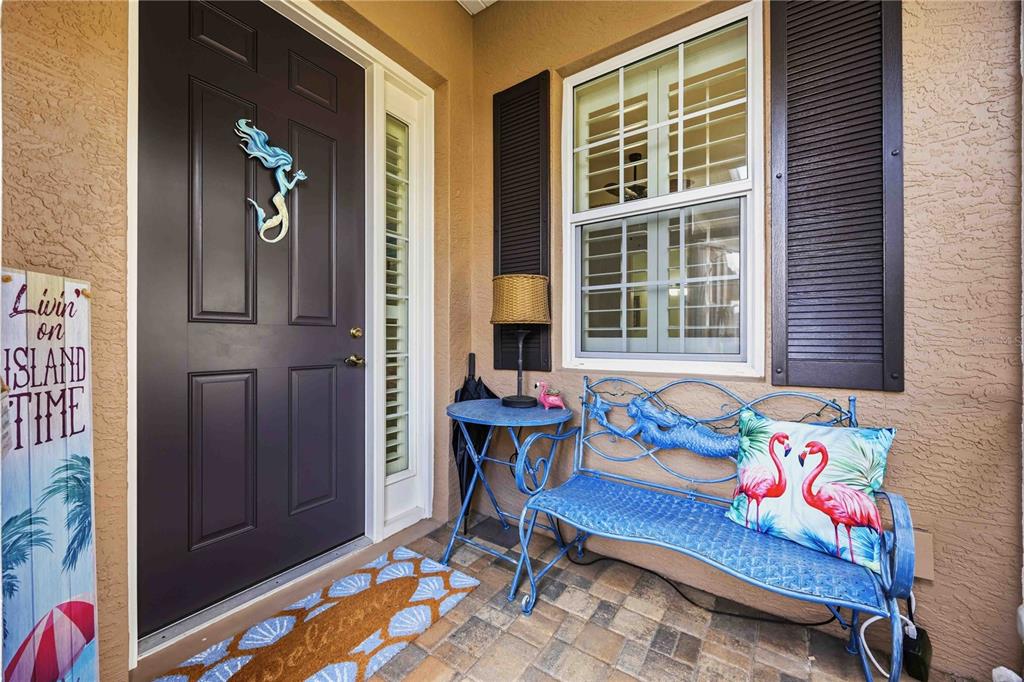 A front porch features a dark door, a blue metal bench, and a welcome mat — 11045 BARNSLEY DRIVE, VENICE, FL