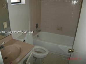 A bathroom features a vanity with a pink countertop, a toilet, and a shower-tub combination — 1318 White Pine Dr, Wellington FL 33414, WELLINGTON, FL