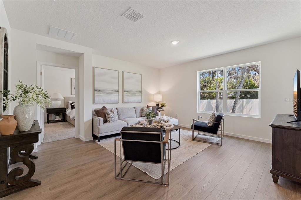 A living room features light wood flooring, a gray sofa, two black chairs, and windows — 5115 NICKERBEAN STREET, APOPKA, FL