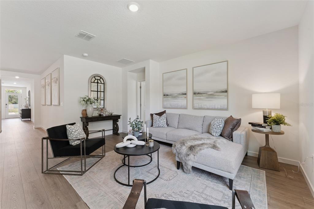 A living room features a grey sectional sofa, two black chairs, and a round coffee table — 5115 NICKERBEAN STREET, APOPKA, FL