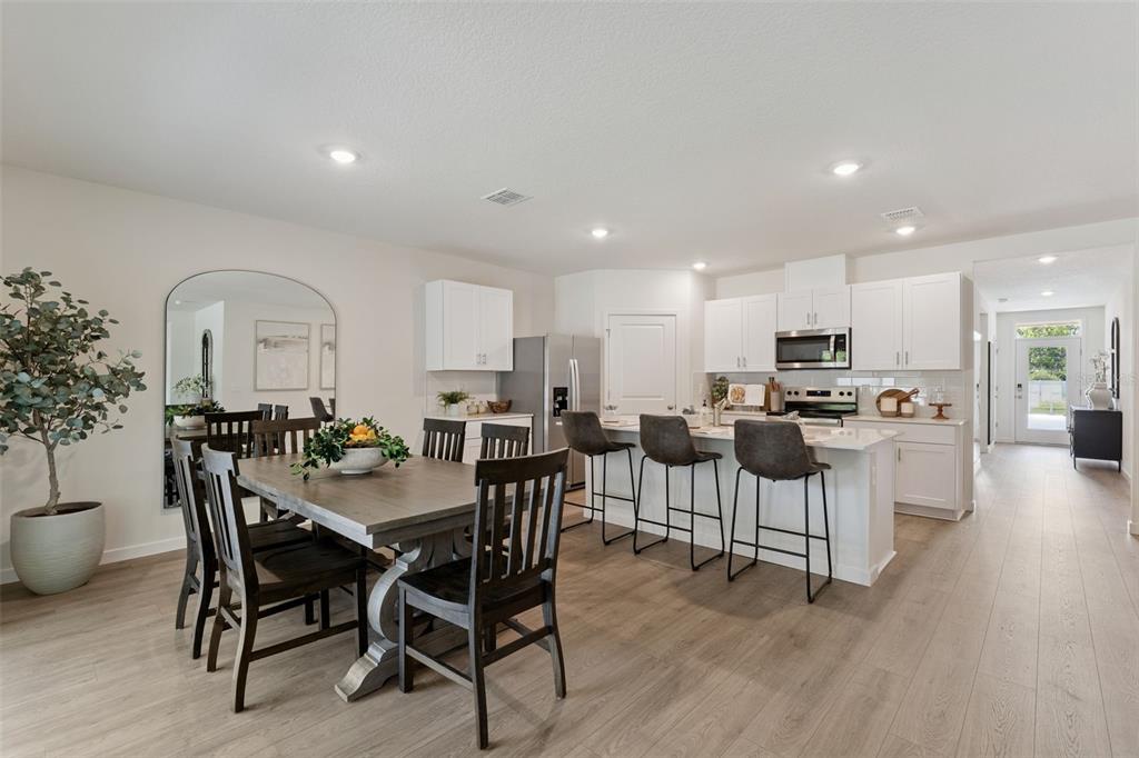 A dining area and kitchen with white cabinetry, a central island, and wood-look flooring — 5115 NICKERBEAN STREET, APOPKA, FL