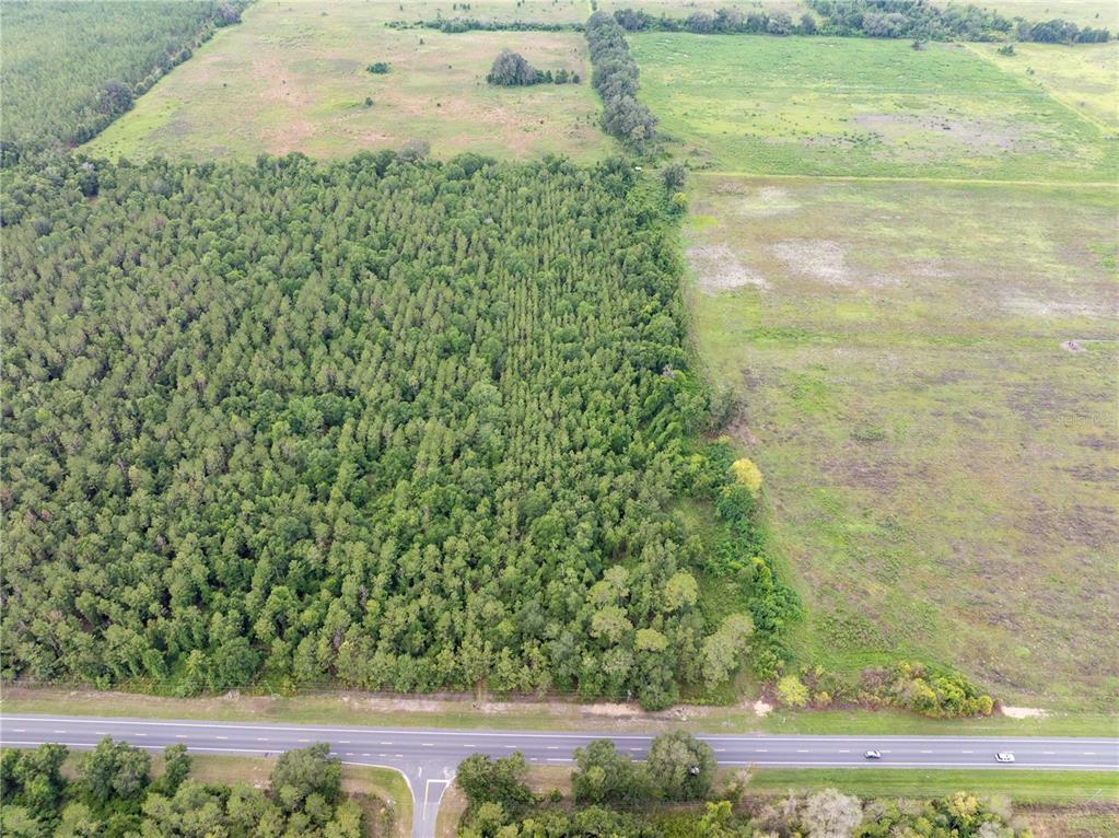An aerial view shows a large plot of land with forest and open fields beside a highway — 17198 SW STATE ROAD 47, FORT WHITE, FL
