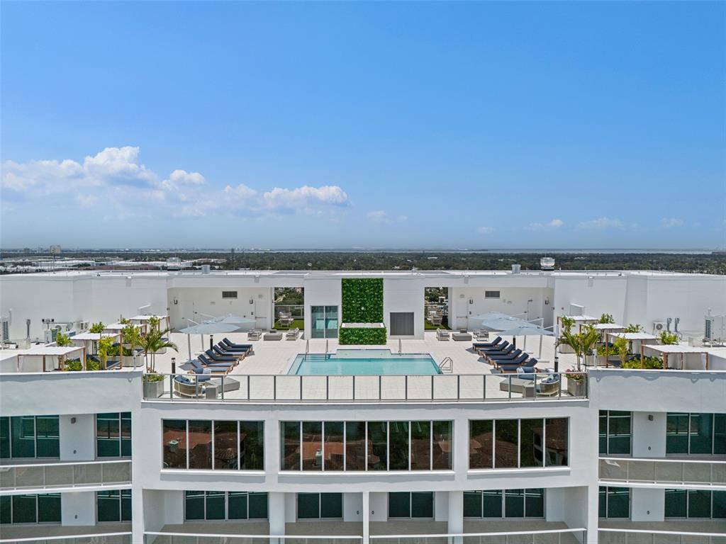 An aerial view of a rooftop swimming pool deck with lounge chairs and cabanas — 5713 BOWEN DANIEL DR. UNIT 1506, TAMPA, FL