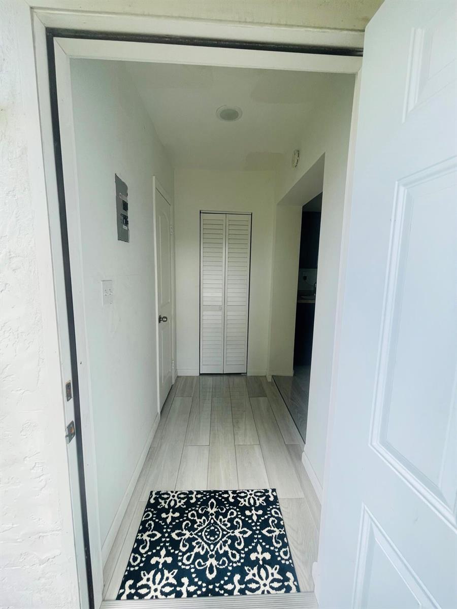 A view through an open doorway into a hallway with light wood-look flooring — 11361 NW 32nd Place, Sunrise FL 33323, SUNRISE, FL