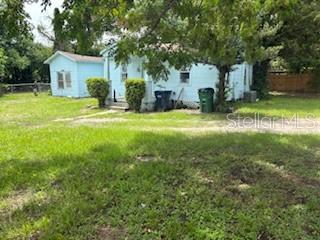 A light blue house with a detached shed sits on a grassy lot with trees — 2901 E YUKON STREET, TAMPA, FL