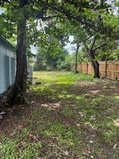 A grassy backyard area features mature trees and a wooden fence along the property line — 2901 E YUKON STREET, TAMPA, FL