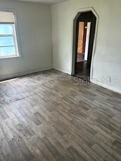 A room with gray wood-look flooring, white walls, a window, and an arched doorway — 2901 E YUKON STREET, TAMPA, FL