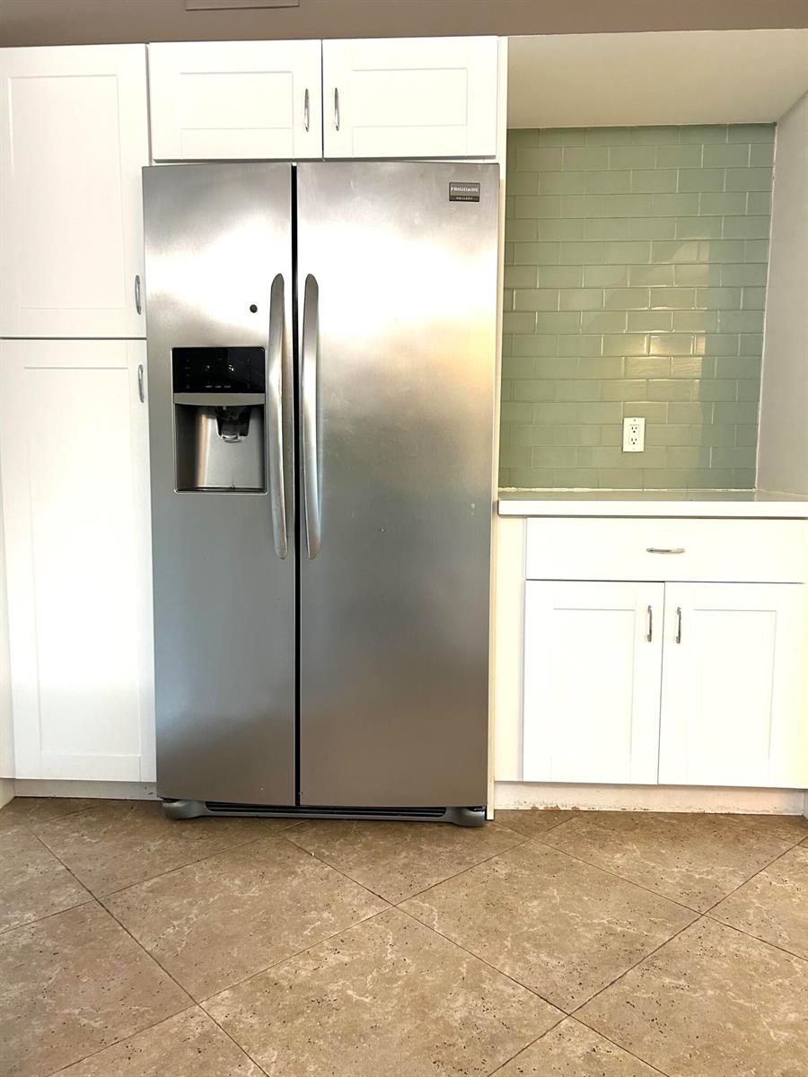 A stainless steel refrigerator sits next to white cabinets and a green subway tile backsplash — 13830 Oneida Drive # G1, Delray Beach FL 33446, DELRAY BEACH, FL
