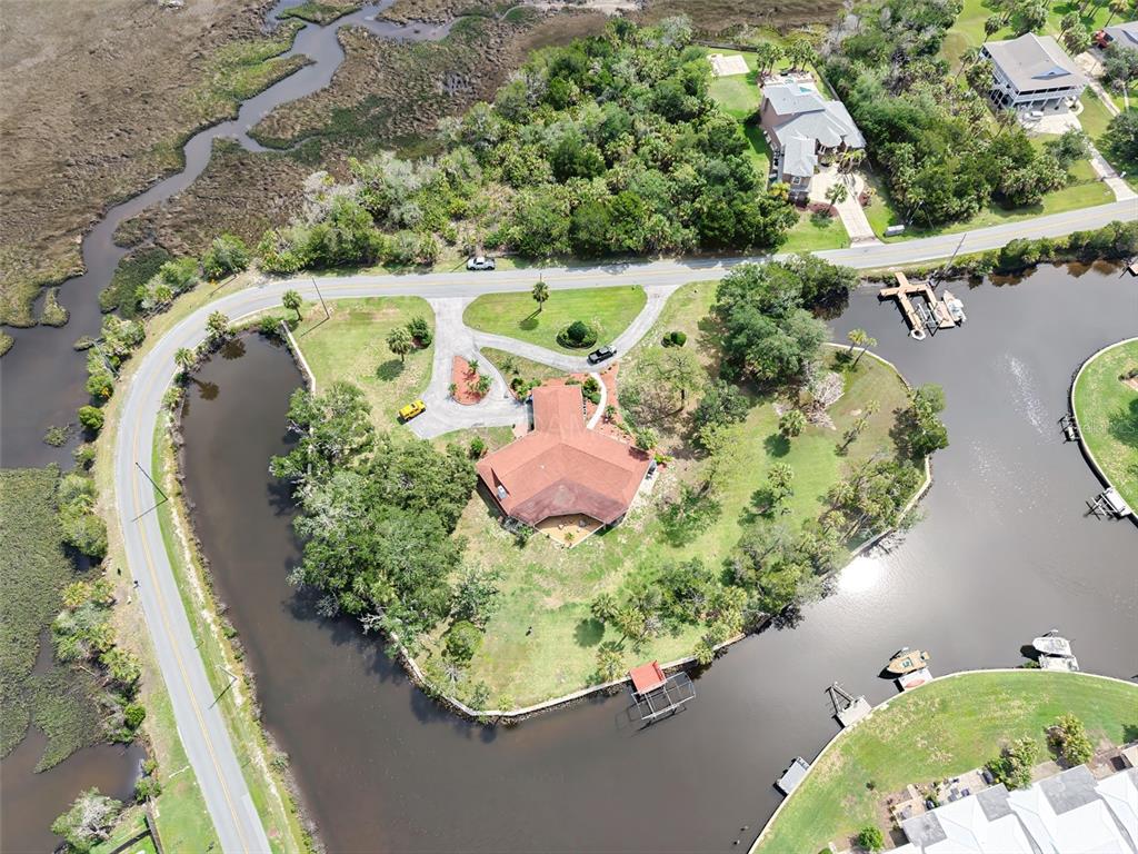 An aerial view of a white single-story house with a red roof near water — 11580 W DIXIE SHORES DRIVE, CRYSTAL RIVER, FL
