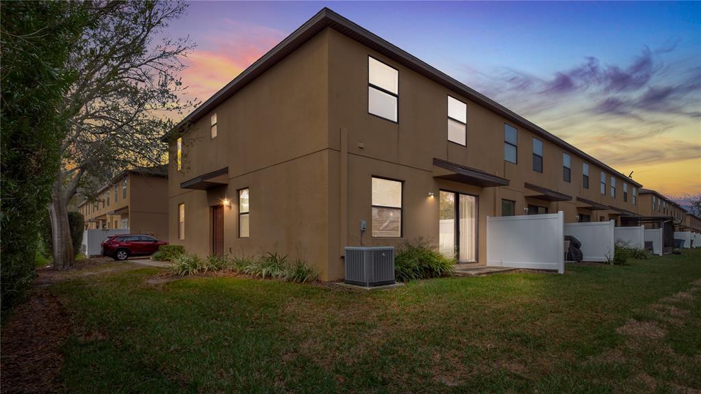 The exterior of a two-story brown townhouse features a small patio and a grass lawn — 10235 VILLA PALAZZO COURT, TAMPA, FL