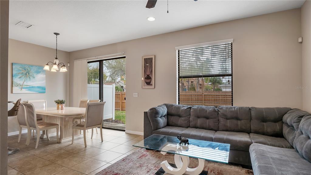 A living and dining area features a gray sectional sofa, glass coffee table, and table — 10235 VILLA PALAZZO COURT, TAMPA, FL