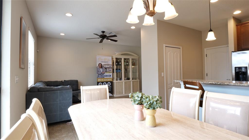 A dining area with a light-colored table and chairs sits adjacent to a living room — 10235 VILLA PALAZZO COURT, TAMPA, FL