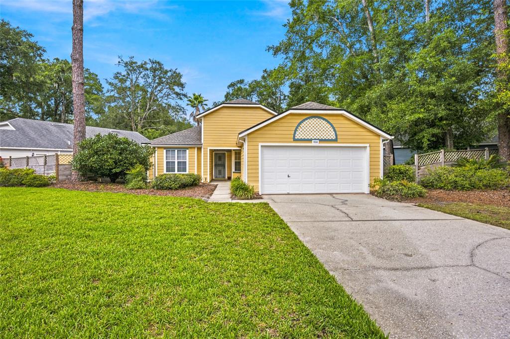 A yellow single-story house features a white garage door, a front entrance, and a lawn — 1034 NW 122ND TERRACE, NEWBERRY, FL