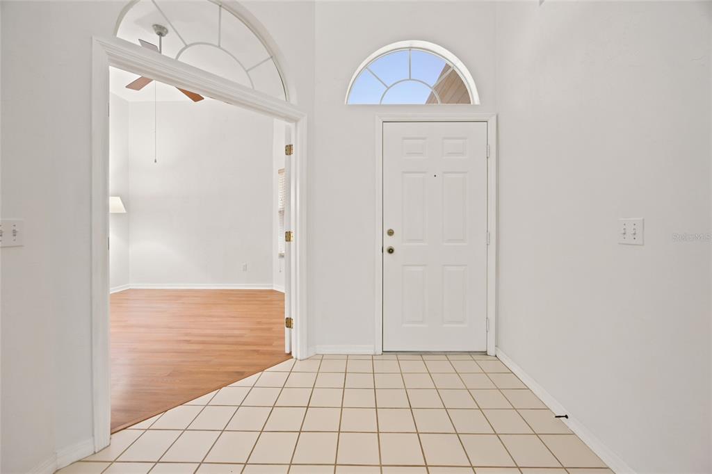An entryway features white walls, a tiled floor, a front door, and an arched transom — 1034 NW 122ND TERRACE, NEWBERRY, FL