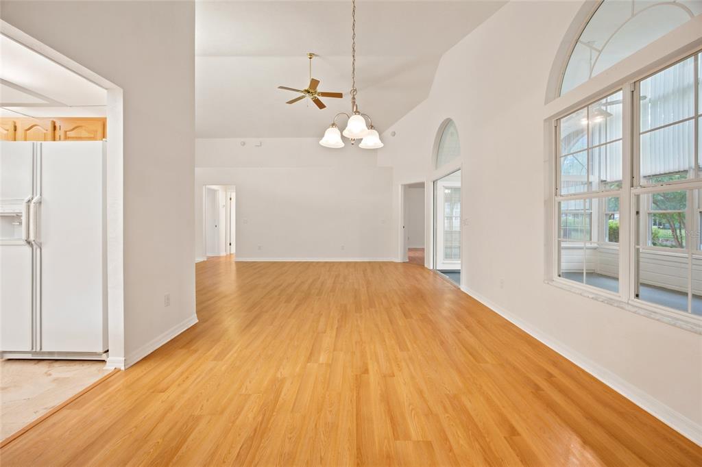 A bright living and dining area features vaulted ceilings, wood-look flooring, and neutral-toned furniture — 1034 NW 122ND TERRACE, NEWBERRY, FL