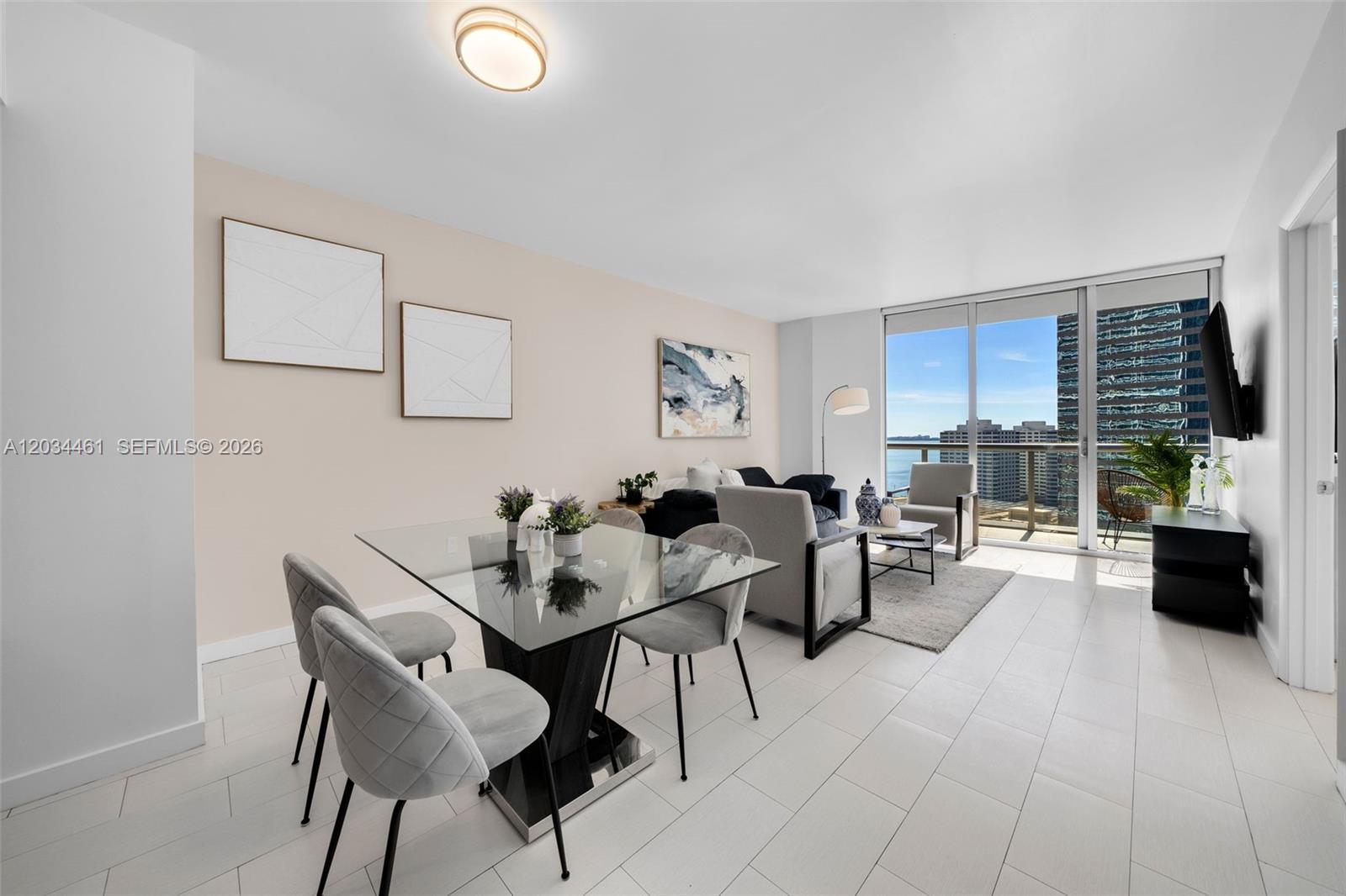 A modern living and dining area features a glass table, gray chairs, and balcony views — 485 Brickell Ave # 1709, Miami FL 33131, MIAMI, FL