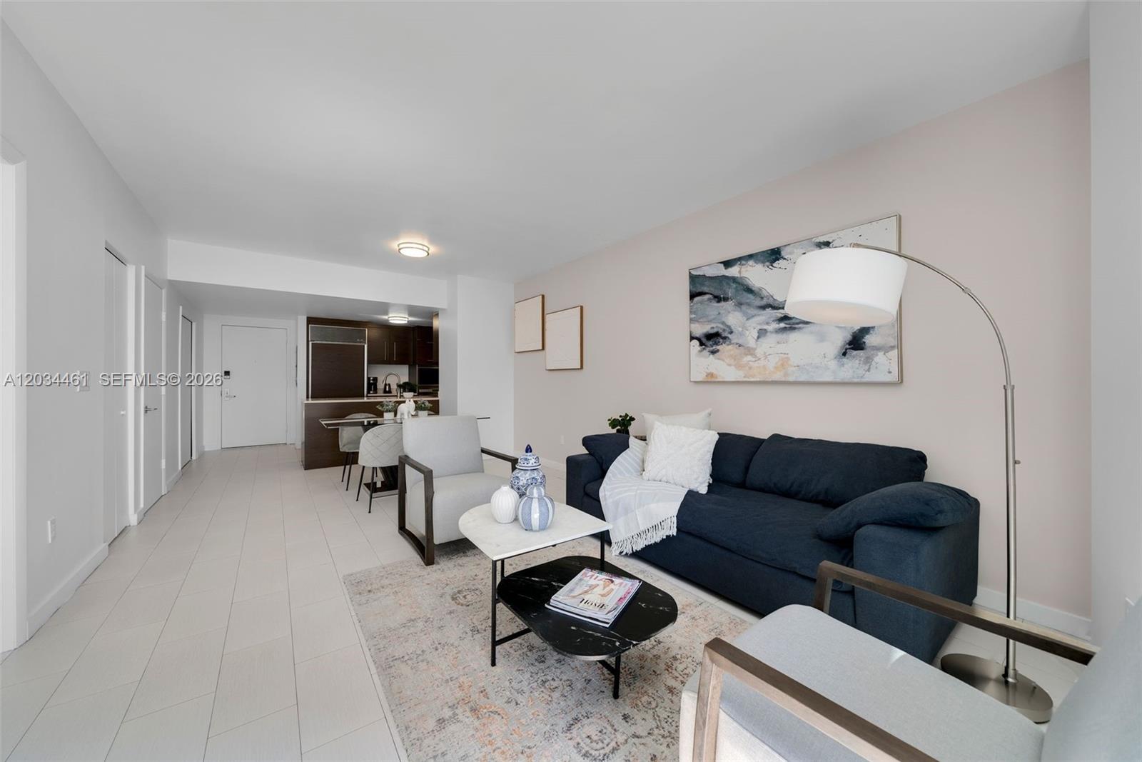 A living room features a blue sofa, two armchairs, a coffee table, and artwork — 485 Brickell Ave # 1709, Miami FL 33131, MIAMI, FL