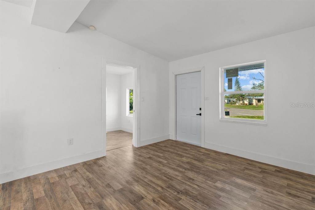 An interior room with white walls, wood-look flooring, a white door, and a window — 2360 EDNOR STREET, PORT CHARLOTTE, FL