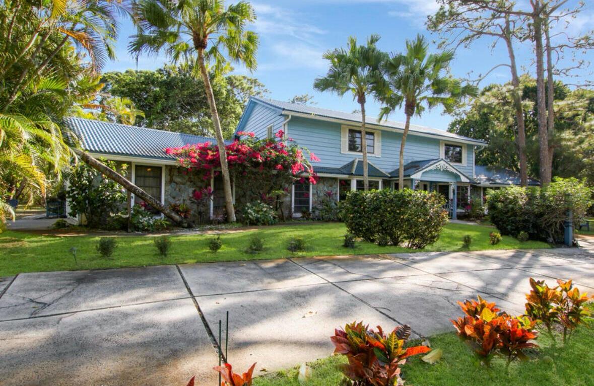 A two-story blue house with a stone facade and a concrete driveway surrounded by palms — 12288 N 165th Rd Road N, FL 33478, FL