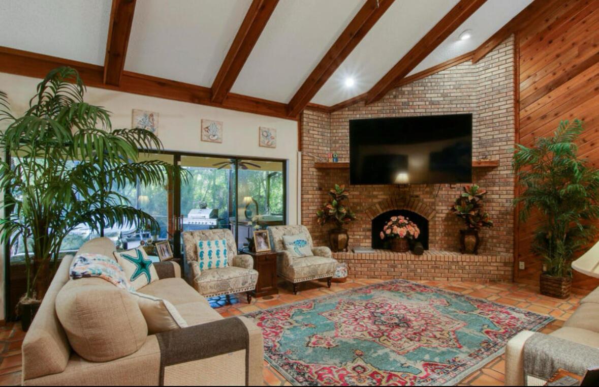 A living room features a brick fireplace, vaulted wood-beam ceilings, tile flooring, and a large rug — 12288 N 165th Rd Road N, FL 33478, FL