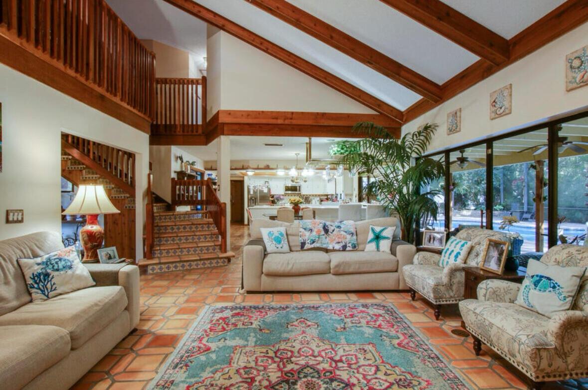 A living room with vaulted wood-beamed ceilings, tile floors, a staircase, and a view outdoors — 12288 N 165th Rd Road N, FL 33478, FL