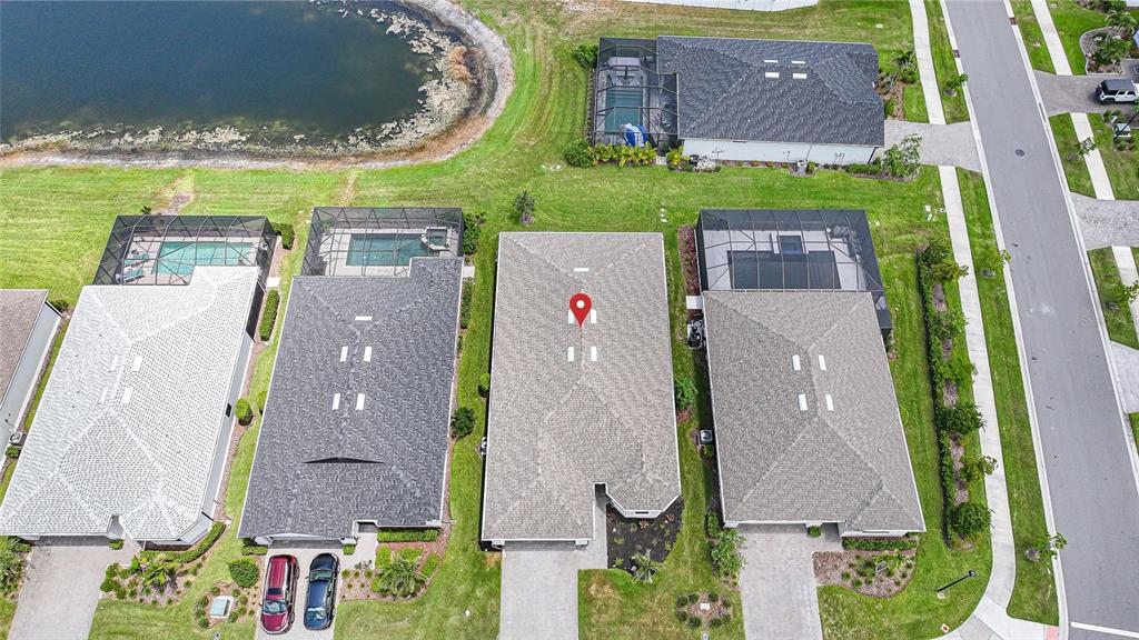 An aerial view shows a suburban neighborhood with several houses, pools, and a nearby pond — 2117 LAURIFOLIA COURT, NORTH PORT, FL