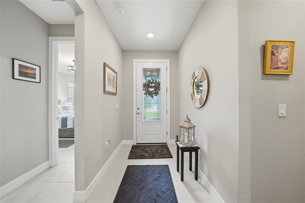 A bright entryway features white tile floors, light gray walls, and a glass-paneled front door — 2117 LAURIFOLIA COURT, NORTH PORT, FL
