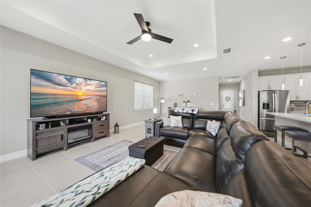 A living room with a large sectional sofa, television console, and an open kitchen area — 2117 LAURIFOLIA COURT, NORTH PORT, FL