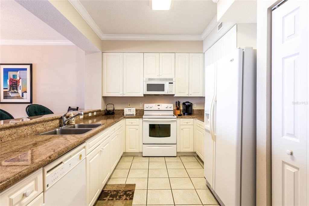 A kitchen features white cabinets, granite countertops, a white stove, and a white refrigerator — 60 SURFVIEW DRIVE UNIT 804, PALM COAST, FL