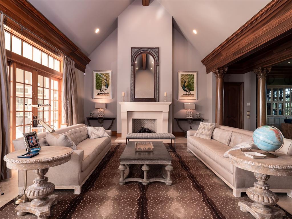 A formal living room features a vaulted ceiling, a stone fireplace, and two beige sofas — 9001 NW 200TH STREET ROAD, MICANOPY, FL